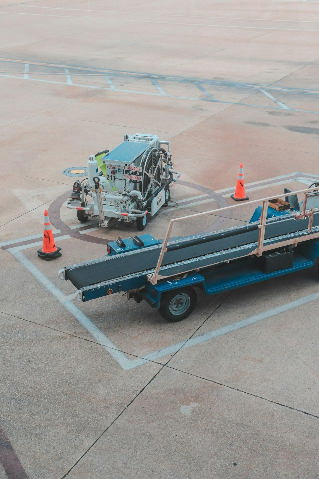 Airport ground power unit and baggage conveyor parked on tarmac.